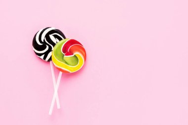 Pembe arka planda beyaz bir çubukta iki renkli lolipop. Üst görünüm, alanı kopyala