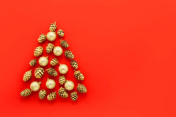 Nieuwjaarskaart. Abstract Kerstboom gemaakt van gouden kegels met decoraties op een rode achtergrond. — Stockfoto
