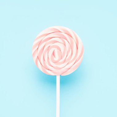 Açık mavi arka planda beyaz bir çubukta pembe lolipop. Düz yat, boşluğu kopyala