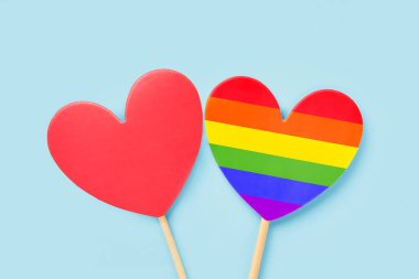 Açık mavi bir arkaplanda kırmızı ve gökkuşağı renkli kalpler. Sevgililer Günü geçmişi. LGBT kavramı