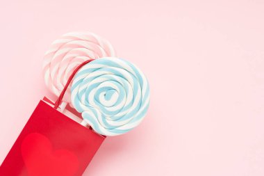 Pembe arka planda iki lolipoplu kırmızı hediye çantası. Teslimat ve alışveriş konsepti. Boşluğu kopyala