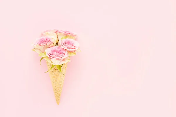 Rosas rosadas en un cono de helado de gofre sobre un fondo rosado. Día de las Madres, San Valentín, despedida de soltera, concepto de verano — Foto de Stock