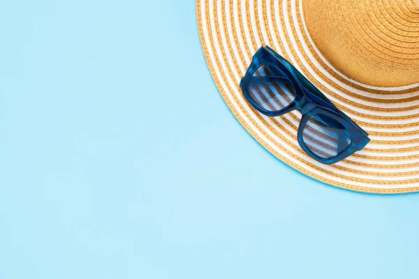 Yaz tatili kavramı. Mavi arka planda çizgili şapka ve güneş gözlüğü. Üst görünüm, alanı kopyala