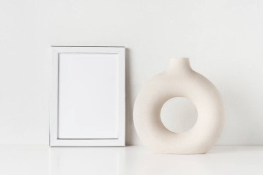 Beyaz çerçeveli maket ve seramik vazo duvardaki beyaz masada. Metin için alanı kopyala