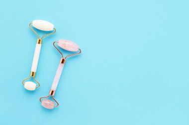 Açık mavi arka planda yüz için iki masaj rulosu. Bencillik, cilt bakımı. Metin için boşluk kopyala, üst görünüm