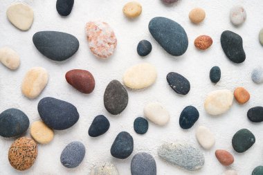 Set of colorful sea stones on white concrete backdrop. Top view, abstract background.
