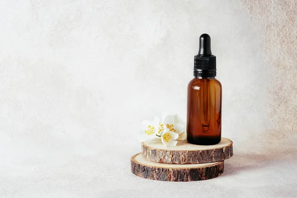 Glass dropper bottles for medical and cosmetic use and jasmine flowers on wooden cut. Natural cosmetic and substantial eco-packaging, SPA concept.