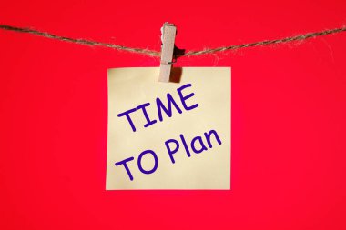 Kırmızı arka planda mandalları olan sarı bir etikete yazı yazma zamanı, konsept fotoğraf.