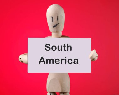 Tahta bir adamın elinde Güney Amerika ifadesi olan bir kart var. İş ve seyahat kavramı.