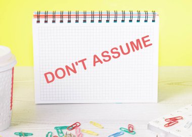 Sarı arka planda masanın üzerinde duran bir not defterine yazı yazma..