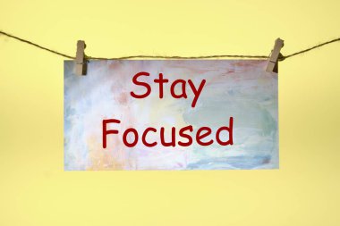 Sarı arkaplandaki ipten sarkıtılmış kağıda yazılmış metni Odakla.