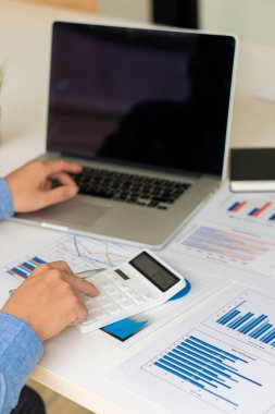 İş adamlarının dikey tablosu, kavramsal iş danışmanlığı ofisinde veri, grafik ve mali raporları analiz eder, tartışır ve beyin fırtınası yapar. Finans hesaplamak için hesap makinesi kullanan bir muhasebeci..