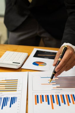 İş adamlarının dikey tablosu, kavramsal iş danışmanlığı ofisinde veri, grafik ve mali raporları analiz eder, tartışır ve beyin fırtınası yapar. Finans hesaplamak için hesap makinesi kullanan bir muhasebeci..