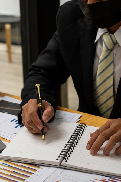 Vertical picture of business people analyzes and discusses and brainstorms data, charts, financial reports in the conceptual work consulting office. An accountant working on a desk using a calculator to calculate finances.