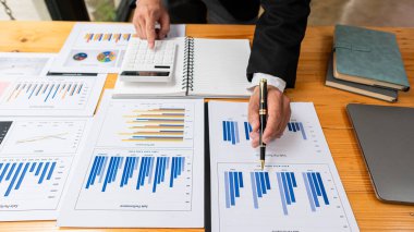 Üst düzey iş adamı elinde kalem tutarak veri tablosunu analiz edip tartışıyor ve beyin fırtınası yapıyor. Finansal rapor kavramı, konsept danışmanlık bürosu. Bir muhasebeci, hesap makinesi kullanarak mali hesapları hesaplıyor..