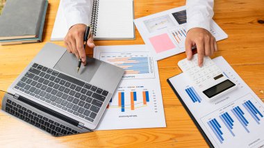 Üst düzey iş adamı elinde kalem tutarak veri tablosunu analiz edip tartışıyor ve beyin fırtınası yapıyor. Finansal rapor kavramı, konsept danışmanlık bürosu. Bir muhasebeci, hesap makinesi kullanarak mali hesapları hesaplıyor..