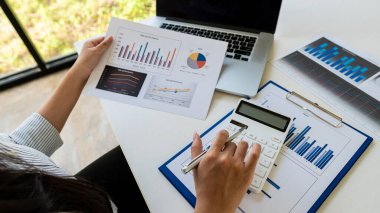 Üst düzey iş adamı elinde kalem tutarak veri tablosunu analiz edip tartışıyor ve beyin fırtınası yapıyor. Finansal rapor kavramı, konsept danışmanlık bürosu. Bir muhasebeci, hesap makinesi kullanarak mali hesapları hesaplıyor..