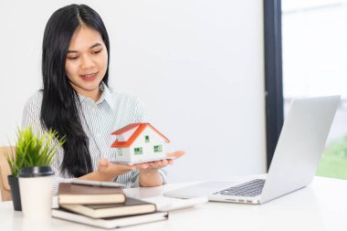 Emlakçılar ofislerde çalışır ve ev satın alma, sigorta veya emlak kredileri için sözleşme imzalamayı tartışan müşteriler. Dizüstü bilgisayar ve defterle masada.