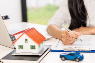 Satış temsilcisi, emlak satın alma veya satma fikri ofisindeki müşterilere ev ya da daire satın almak için bir ev satın alma sözleşmesi sunar..