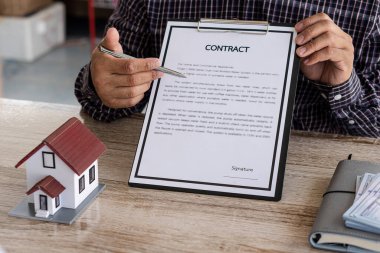 Satış temsilcisi, emlak satın alma veya satma fikri ofisindeki müşterilere ev ya da daire satın almak için bir ev satın alma sözleşmesi sunar..