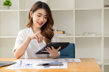 İş kadını veri, çizelge ve mali raporları analiz ediyor ve inceliyor. Laptop ve hesap makinesiyle ofiste. Mali ve yatırım hesaplarıyla çalışma fikirleri.