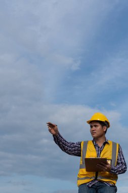 Elinde kağıt Pam ve kalem tutan genç bir mühendis gökyüzünden bir binayı inceliyor..
