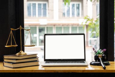 Laptop ve yargıcın çekici ve terazisi. Avukatın masasında hukuk bürosundaki not defteriyle adalet.