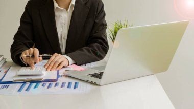 Ofiste kalemle çalışan bir işadamı, hesap makinesi kullanarak mali hesap rakamlarını hesaplar veya finansal uzmanlar grafikleri, grafikleri ve finans kavramlarını analiz eder. bankacılık ve borsa araştırmaları