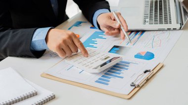 Ofiste kalemle çalışan bir işadamı, hesap makinesi kullanarak mali hesap rakamlarını hesaplar veya finansal uzmanlar grafikleri, grafikleri ve finans kavramlarını analiz eder. bankacılık ve borsa araştırmaları