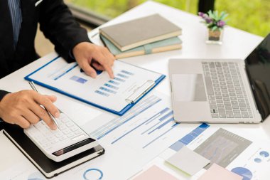 Ofiste kalemle çalışan bir işadamı, hesap makinesi kullanarak mali hesap rakamlarını hesaplar veya finansal uzmanlar grafikleri, grafikleri ve finans kavramlarını analiz eder. bankacılık ve borsa araştırmaları