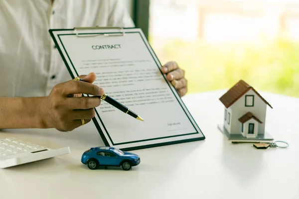 Model cars and houses with agents and customers discussing contracts, insurance, or real estate, or property history loans. Ideas to sell your house, car, or rent at the office desk.