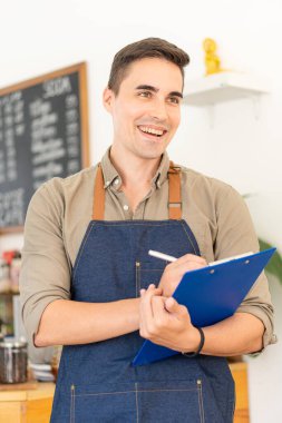 Yakışıklı genç bir dükkan sahibi bir kahve dükkanında mavi bir dosya tutuyor. Müşterilere hizmet etmek için bir dükkan açmaya hazırlanan bir erkek çalışan, yiyecek ve içecek servisi dükkanı açıyor..
