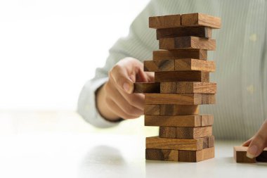 Kızın eli, kuleye çaktırmadan tahta bloğu çıkarmaya çalıştı. Tahta bloklarla yapılan fiziksel yetenek oyunu. İnşaat işi risk kavramı.