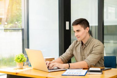 Elinde kalem tutan işadamı, pazarlama planını hesap makinesi ve dizüstü bilgisayarla ofis finans ve muhasebe kavramlarındaki ahşap masa üzerinde analiz etmek için grafiğe işaret ediyor.