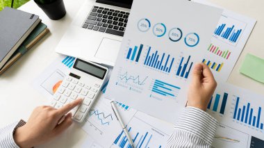 İş adamları grafikleri analiz etmek ve raporları, şirket finans bütçelerini ve başarılı bir iş konsept ofisinde gelecek için plan yapmak için dizüstü bilgisayar ve hesap makinesi kullanırlar..
