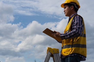 Profesyonel mühendisler, mimarlar, miğfer takan işçiler ve ev inşaatındaki kalemlerle ellerinde kağıt işleri..