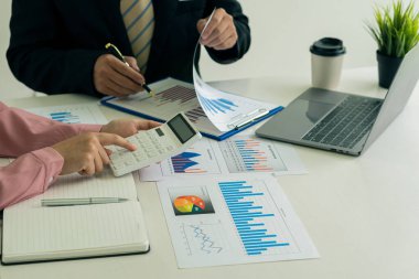 Elinde kalem tutan iki işadamı, şirketin mali durumunun analizini hesaplamak için grafiği işaret ediyor. Belge grafikleriyle çalış Borsa, ofis, vergi için imaj kavramı