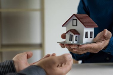Satıcılar, ev satış sözleşmesini kabul ettikten sonra yeni sahiplerine ev öneriyorlar. Bir emlakçının ev sahibi olma anlaşmasını müşterilere açıklayan bir imajını kiralamak ve satın almak.
