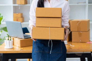 Küçük işletme, KOBİ, serbest meslek, akıllı telefon, laptop, çevrimiçi, pazarlama, ambalaj, nakliye, KOBİ, e-ticaret ve dağıtım konseptiyle ev portresi üzerinde çalışan genç bir kadın..