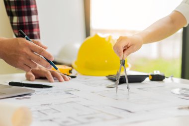 Projenin planları üzerinde çalışan iki erkek ve kadın mühendis, ofis konseptlerinde modeller ve mühendislik araçları yaratmak için ortaklarla birlikte çalıştı..