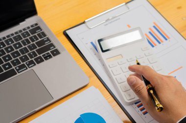 Bir iş adamı ya da muhasebeci bir kalem tutar ve iş bilgilerini hesaplamak için hesap makinesine basar. Mali muhasebe grafik dökümanı ve şirket ofisindeki defter bilgisayarı.