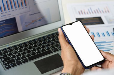 İş yerinde teknoloji pazarlama reklamları için yer ararken elinde beyaz ekranlı siyah bir cep telefonu olan bir kadının üst görünümü.
