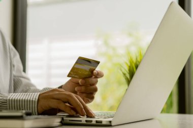 Kredi kartı tutan ve dizüstü bilgisayar kullanan genç bir kadın çevrimiçi alışveriş, e-ticaret, internet bankacılığı, harcama parası, ev konseptinden çalışma ve çevrimiçi ödeme