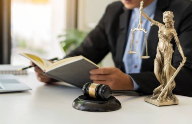 Adalet tanrıçası, erkek bir avukatın önüne dizilmiş ve dizüstü bilgisayarın yasal konsepti üzerinde çalışan bir çekiçle. Avukatlık Bürosunda Adalet Danışmanlığı