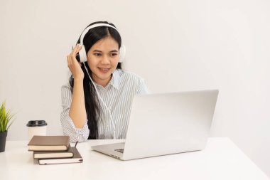 Genç öğrenciler çevrimiçi çalışmak için bilgisayar kullanır. Çevrimiçi eğitim ve Asyalı kadın öğrenimi masasında oturup yaratıcı işler yaparken dizüstü bilgisayar teknolojisi kullanıyor. ev kavramından çalışma