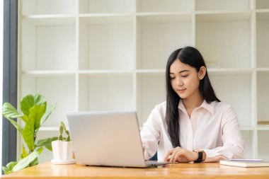Genç öğrenciler çevrimiçi çalışmak için bilgisayar kullanır. Çevrimiçi eğitim ve Asyalı kadın öğrenimi masasında oturup yaratıcı işler yaparken dizüstü bilgisayar teknolojisi kullanıyor. ev kavramından çalışma