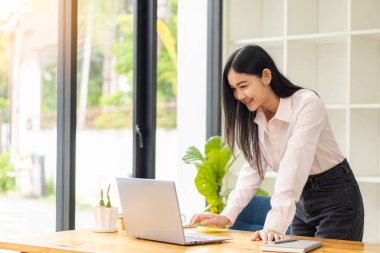 Genç öğrenciler çevrimiçi çalışmak için bilgisayar kullanır. Çevrimiçi eğitim ve Asyalı kadın öğrenimi masasında oturup yaratıcı işler yaparken dizüstü bilgisayar teknolojisi kullanıyor. ev kavramından çalışma