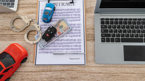 Toy car, keys, and laptop with money, pens, contract documents on the table. car trading ideas