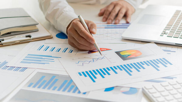 business woman holding documents with financial statistics Data analysis charts and graphs and calculators. financial concept close-up holding a pen and pointing at a financial document