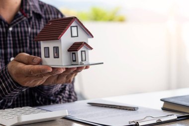 Bir emlakçı anlaşmayı imzalamak için örnek bir ev sigortası öneriyor. Satış sözleşmesinin belgeleriyle ya da kira sözleşmesiyle